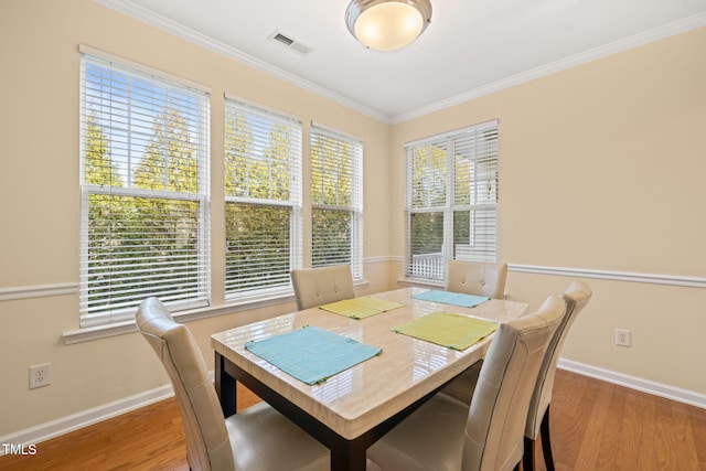 dining room featuring baseboards, wood finished floors, visible vents, and crown molding