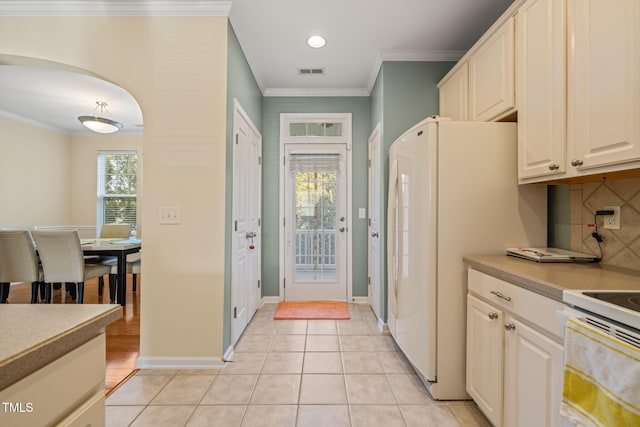 kitchen featuring light tile patterned floors, visible vents, arched walkways, and crown molding