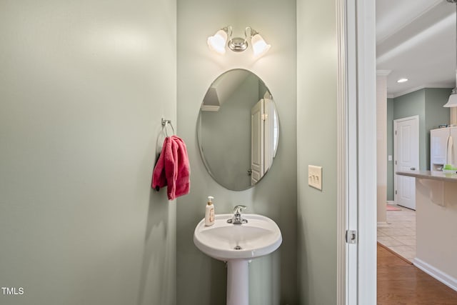 bathroom featuring crown molding, baseboards, and wood finished floors