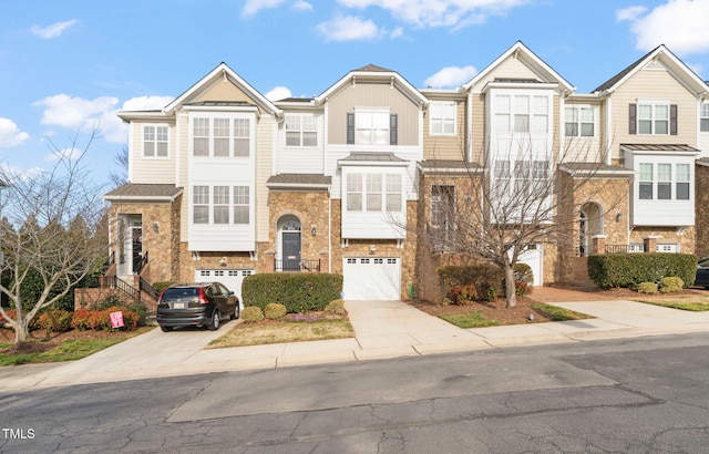 townhome / multi-family property featuring stone siding, concrete driveway, brick siding, and an attached garage