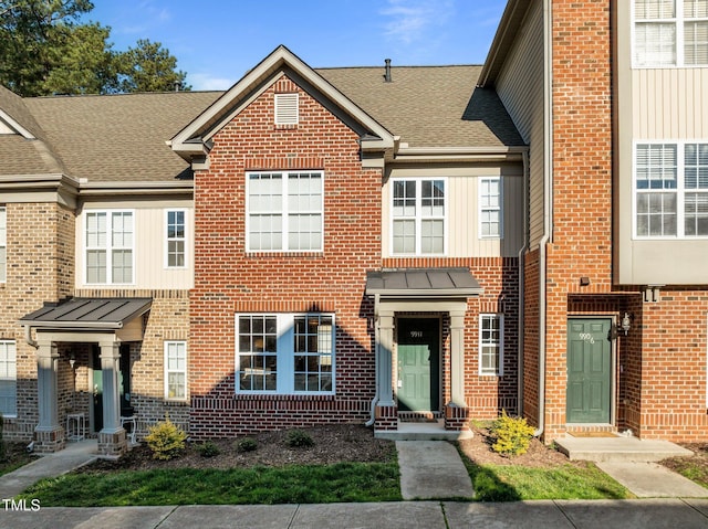 multi unit property with roof with shingles and brick siding