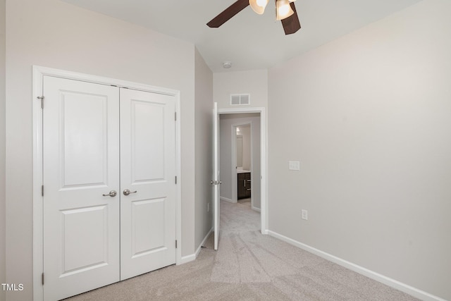 unfurnished bedroom featuring ceiling fan, visible vents, baseboards, light colored carpet, and a closet