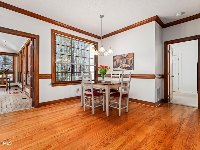 dining space featuring crown molding, light wood finished floors, visible vents, and a healthy amount of sunlight