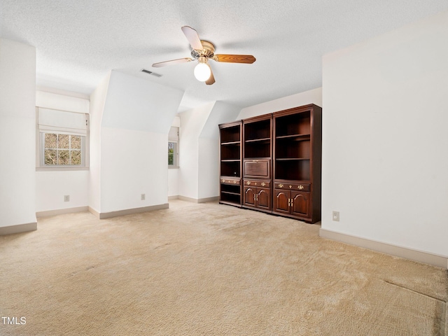 empty room with ceiling fan, visible vents, a textured ceiling, and light colored carpet