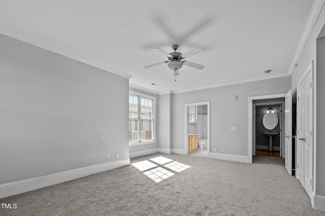 unfurnished bedroom with light carpet, baseboards, a ceiling fan, ornamental molding, and ensuite bathroom