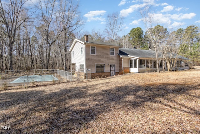 back of property featuring brick siding, a chimney, and fence