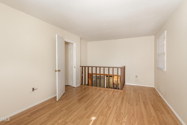 spare room featuring baseboards and light wood finished floors