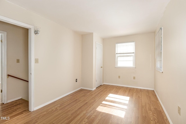 spare room featuring baseboards and light wood finished floors