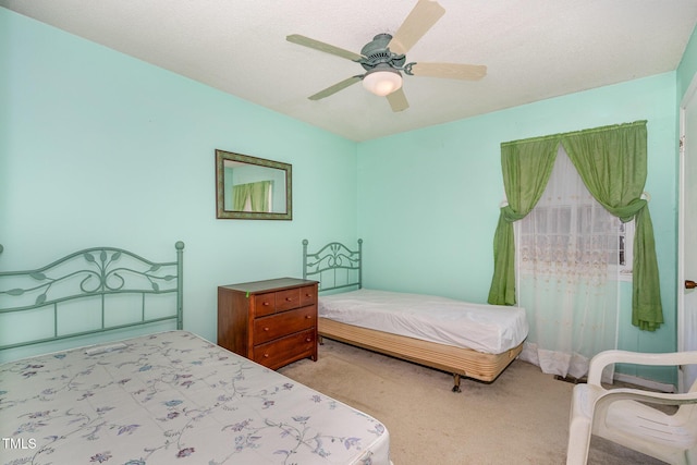 carpeted bedroom with ceiling fan and a textured ceiling