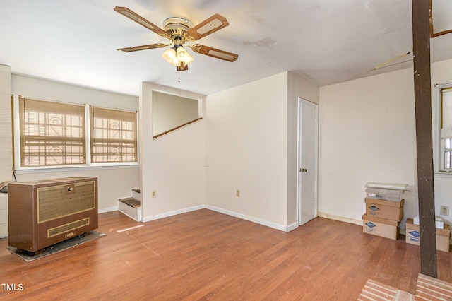 unfurnished living room featuring a ceiling fan, stairway, baseboards, and wood finished floors