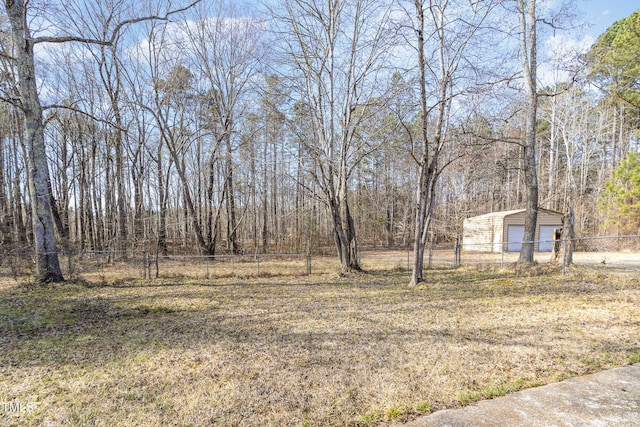 view of yard featuring an outbuilding, a detached garage, and fence