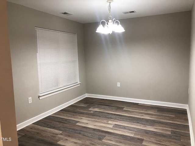 unfurnished room featuring dark hardwood / wood-style floors and an inviting chandelier