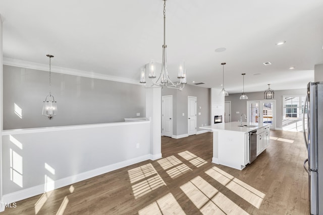 kitchen featuring a center island with sink, stainless steel appliances, a notable chandelier, and decorative light fixtures