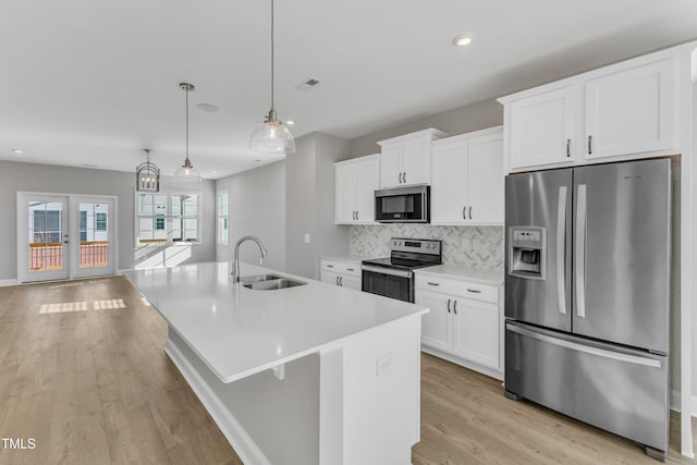 kitchen featuring hanging light fixtures, a kitchen island with sink, stainless steel appliances, light countertops, and a sink