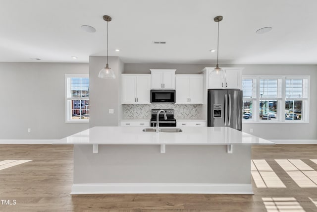 kitchen with white cabinets, a spacious island, stainless steel appliances, and decorative light fixtures