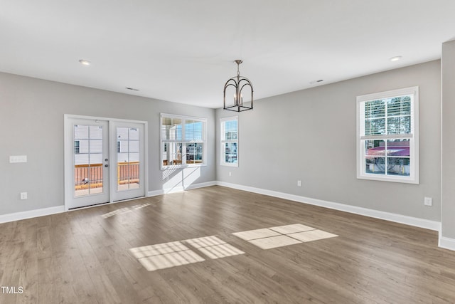 interior space featuring baseboards, french doors, wood finished floors, and a healthy amount of sunlight