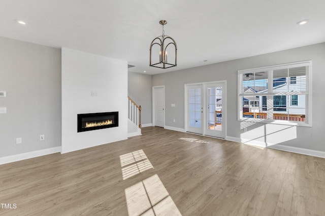 unfurnished living room with a large fireplace, recessed lighting, baseboards, and light wood-style floors