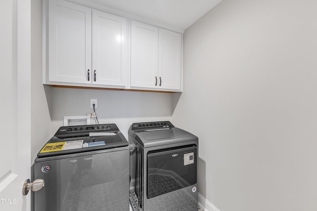 clothes washing area featuring cabinet space, baseboards, and washer and dryer