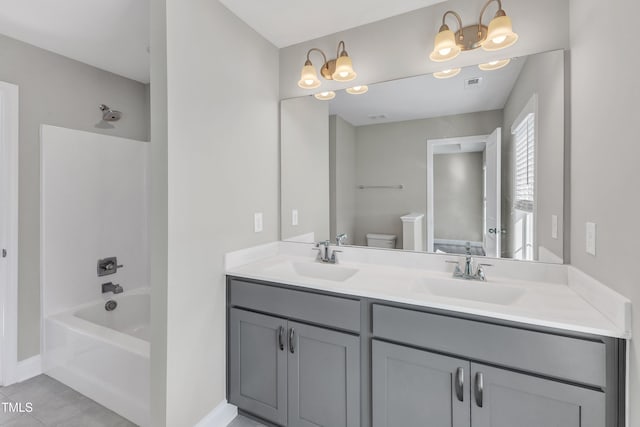 bathroom featuring tub / shower combination, a sink, toilet, and double vanity