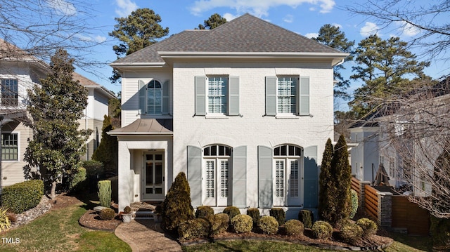 view of front facade featuring roof with shingles and brick siding