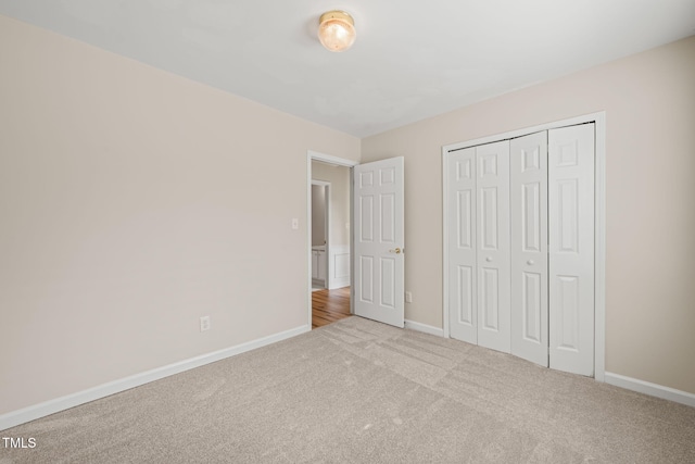 unfurnished bedroom featuring carpet floors, baseboards, and a closet