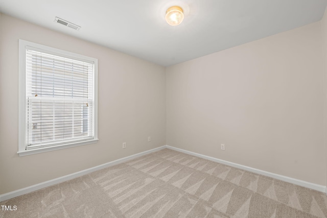 spare room with light colored carpet, visible vents, and baseboards