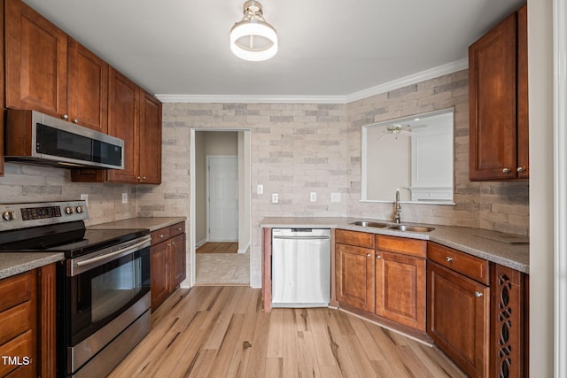 kitchen with appliances with stainless steel finishes, decorative backsplash, a sink, and light wood-style floors