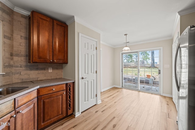 kitchen with light wood-style floors, tasteful backsplash, ornamental molding, and freestanding refrigerator