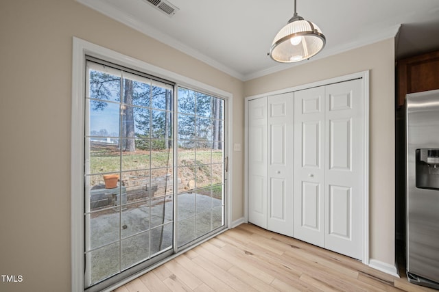 interior space featuring light wood finished floors, visible vents, ornamental molding, stainless steel refrigerator with ice dispenser, and a closet