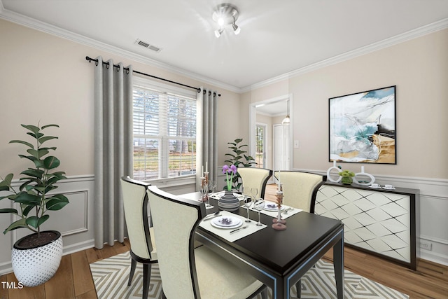 dining room with ornamental molding, visible vents, and wood finished floors