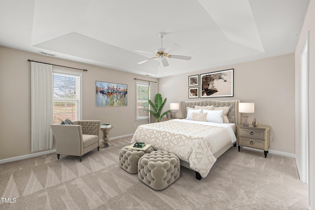 bedroom featuring a tray ceiling, light colored carpet, visible vents, and multiple windows