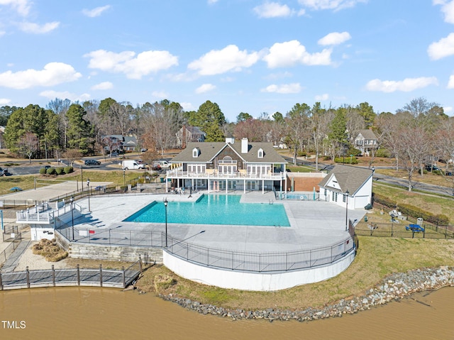 community pool featuring a water view, fence, and a patio