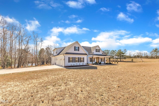 view of front of house featuring a porch, board and batten siding, a standing seam roof, metal roof, and driveway