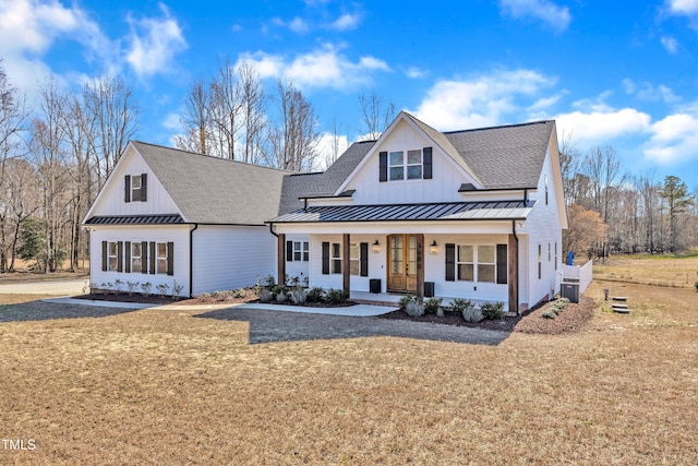 modern farmhouse with a shingled roof, covered porch, a front lawn, and a standing seam roof