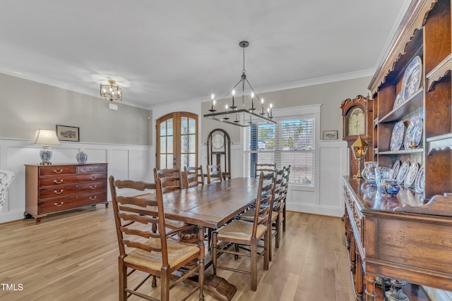 dining space with arched walkways, a notable chandelier, a wainscoted wall, french doors, and light wood finished floors