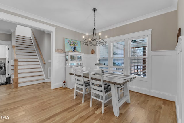 dining area featuring a wainscoted wall, crown molding, light wood finished floors, visible vents, and stairs