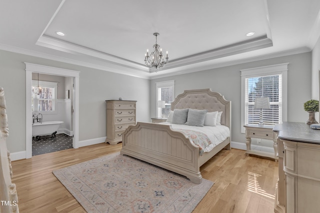 bedroom featuring light wood-style floors, ornamental molding, a raised ceiling, and a notable chandelier