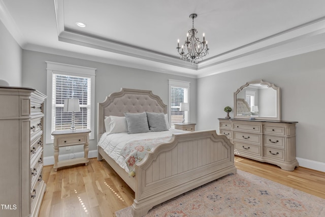 bedroom featuring baseboards, a raised ceiling, crown molding, light wood-type flooring, and a chandelier