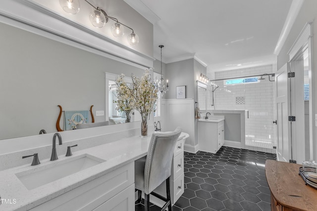 full bath featuring two vanities, a sink, ornamental molding, tile patterned floors, and a stall shower