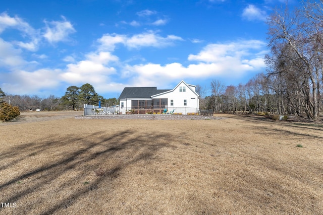 rear view of property featuring a yard and a sunroom