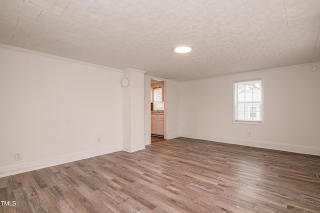 empty room with hardwood / wood-style floors and ornamental molding