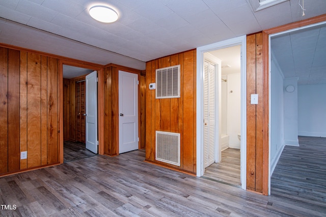 spare room featuring light hardwood / wood-style flooring and wood walls