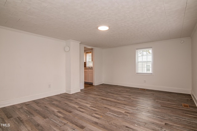 empty room with dark wood-type flooring and ornamental molding