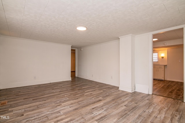 empty room featuring wood-type flooring and crown molding