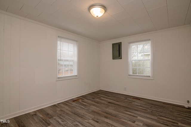 empty room featuring ornamental molding, dark wood-type flooring, and electric panel