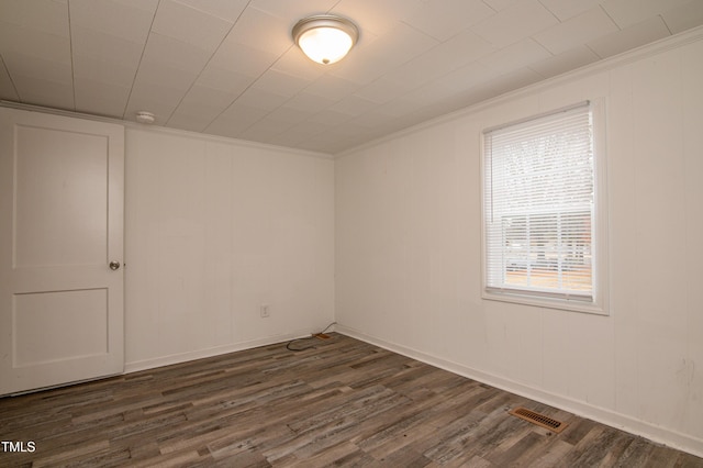 empty room with ornamental molding and dark hardwood / wood-style floors