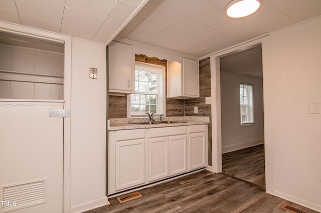 kitchen with sink, dark wood-type flooring, white cabinets, and backsplash