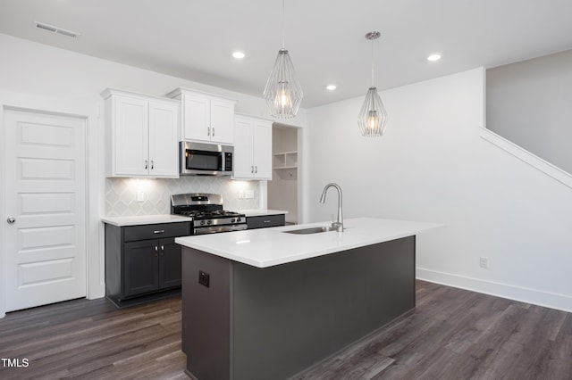 kitchen with sink, a center island with sink, appliances with stainless steel finishes, pendant lighting, and white cabinets