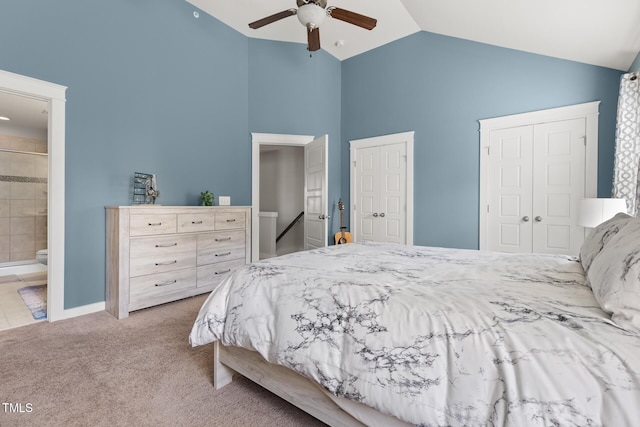 bedroom featuring ensuite bathroom, high vaulted ceiling, light colored carpet, ceiling fan, and multiple closets