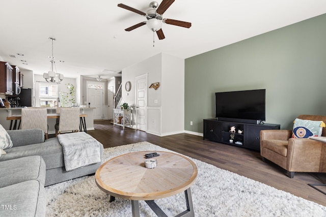 living room featuring ceiling fan with notable chandelier and dark wood-type flooring